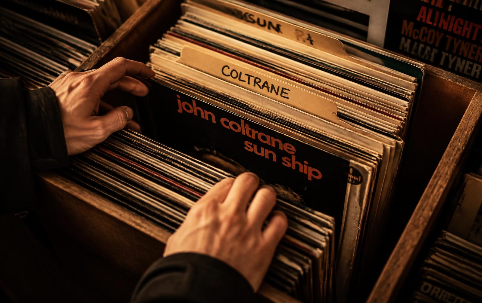 Hands flipping through a crate of vinyl records in a record shop
